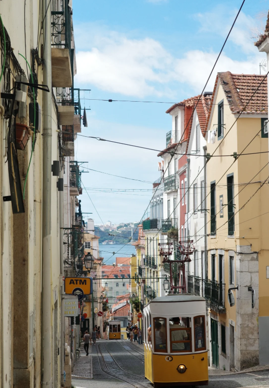 A typical street in the Alfama district of Lisbon, with ancient buildings and iconic yellow trams.